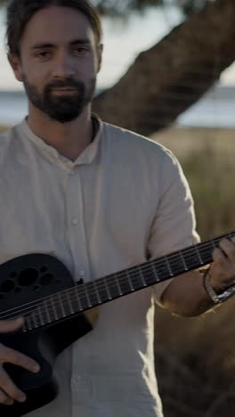 man playing an acoustic guitar outdoors