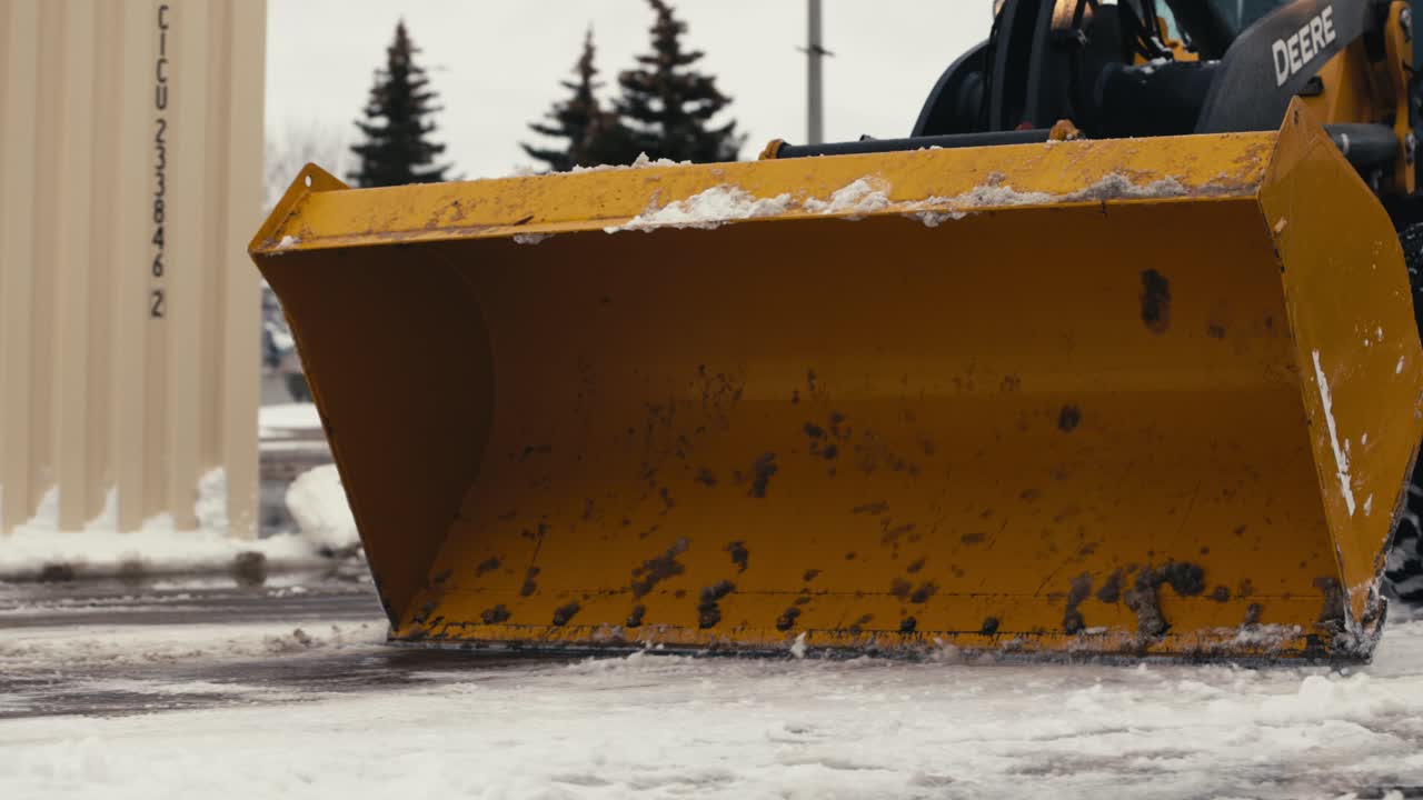 Close-up of a snowplow blade pushing snow on a street