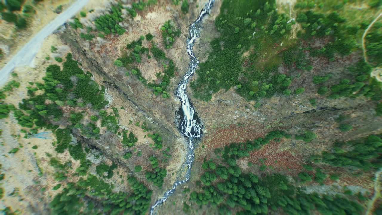 Drone flying high above Bâlea Waterfall in Romania, rising slowly, with the waterfall centered in frame, river path visible, surrounded by green autumn forest