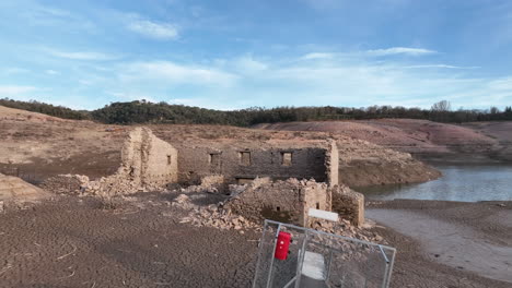 muelle inaccesible inutilizable y ruinas de edificios en las costas secas del pantano de sau en cataluña, españa