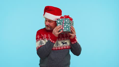 Funny-man-wears-Christmas-sweater-with-deers-received-present,-interested-in-what-inside-gift-box