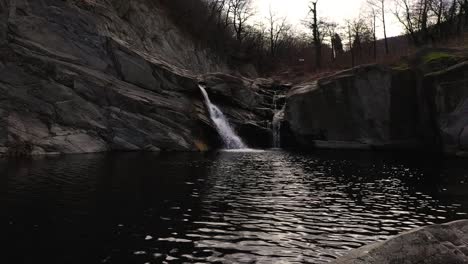 Drohnenflug-über-Einige-Steine-Und-Einen-Wasserfall-Tagsüber-In-Der-Nähe-Eines-Steins