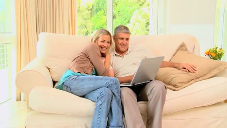 Couple-enjoying-pictures-on-laptop-on-sofa