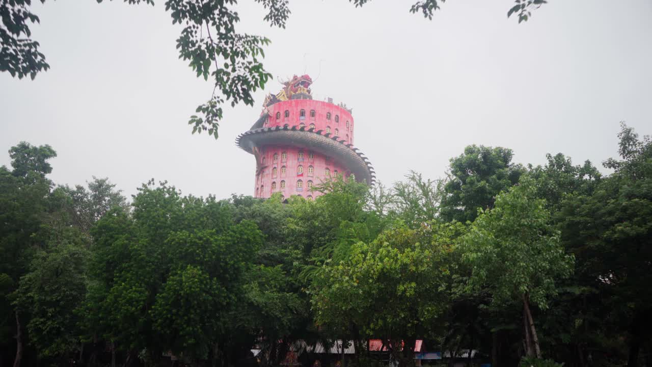 un edificio de estilo chino con un enorme dragón enrollado alrededor y protegiendo el templo wat samphran en tailandia