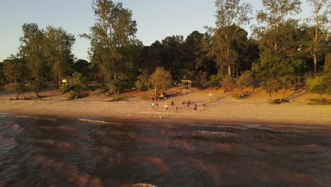 group of friends playing beach volleyball at sunset along fray bentos shore in uruguay
