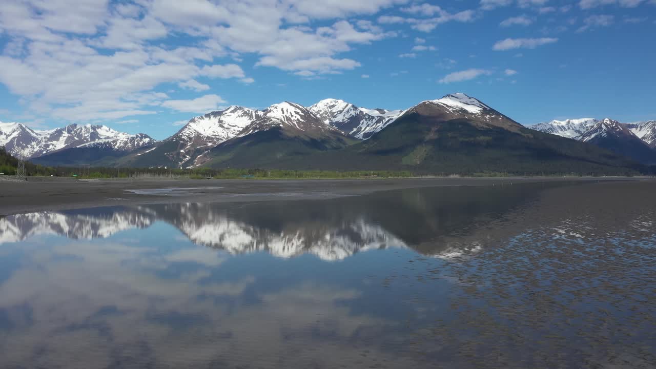 el avión no tripulado se eleva sobre las brillantes aguas del brazo de turnagain en alaska con majestuosos picos nevados de las montañas chugach en la península de kenai en el fondo