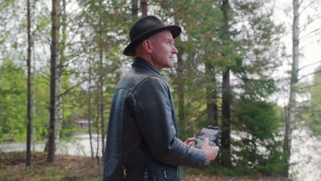 caucasian model operating a drone in the forest and looking from device to the sky