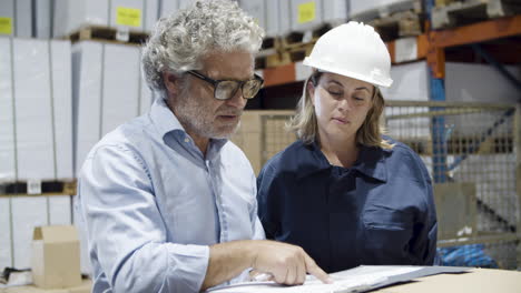 serious safety inspector checking warehouse with female worker