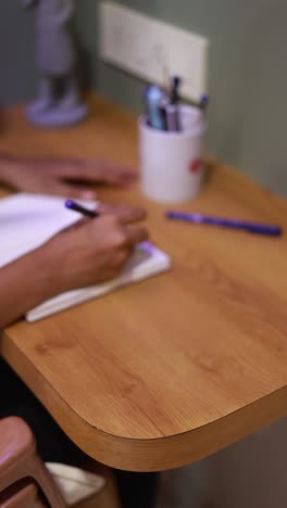 a man writing a homework on the wooden table