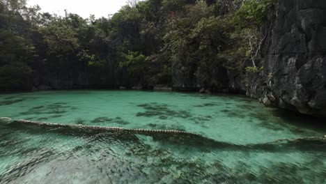 fpv drone shot of shallow turquoise water bay and caves in coron, palawan - philippines