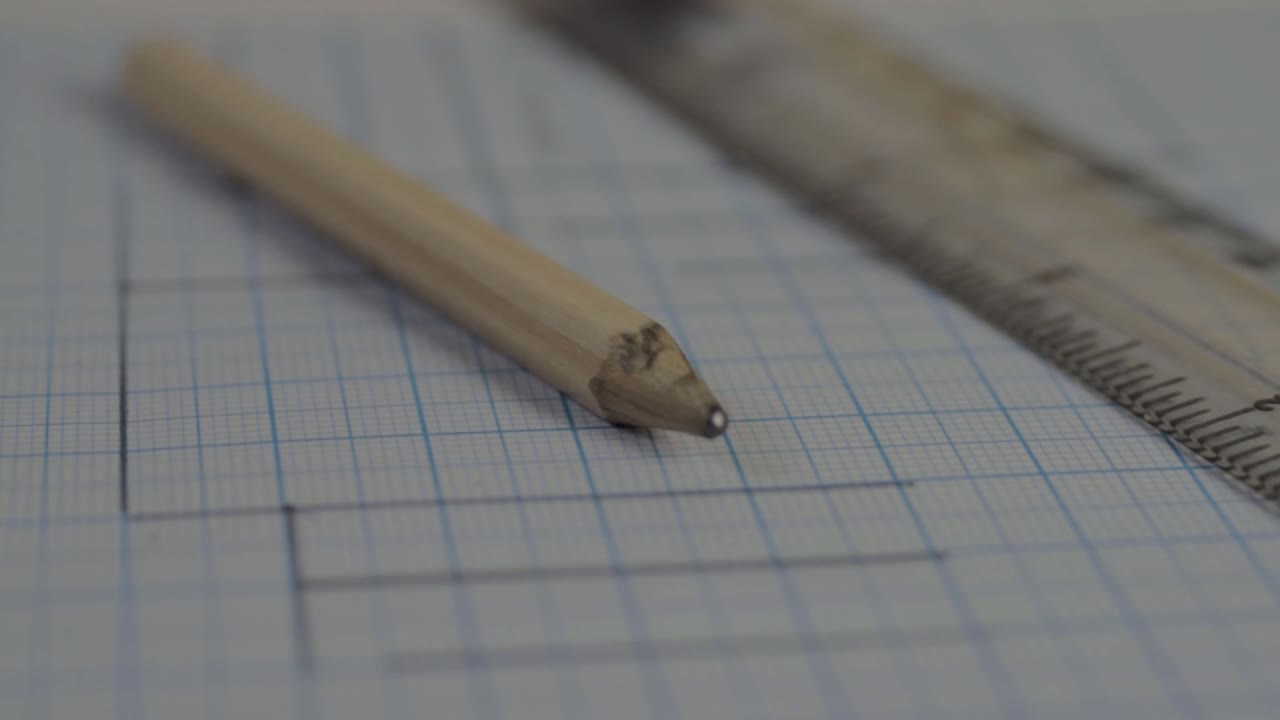 Pencil and drawings on graph paper with ruler close up panning
