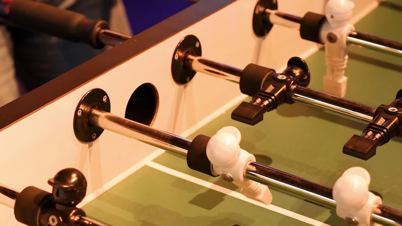 Detailed view of players' hands maneuvering foosball rods during an intense match.