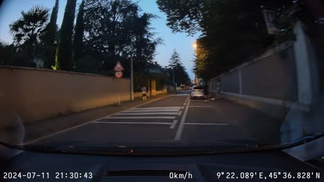 pov a parked car pulls out and drives down narrow streets at dusk, dash cam video