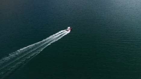 aerial view of the speedy motorboat riding the waters of the fjord, leaving waves and a stream of white foam behind