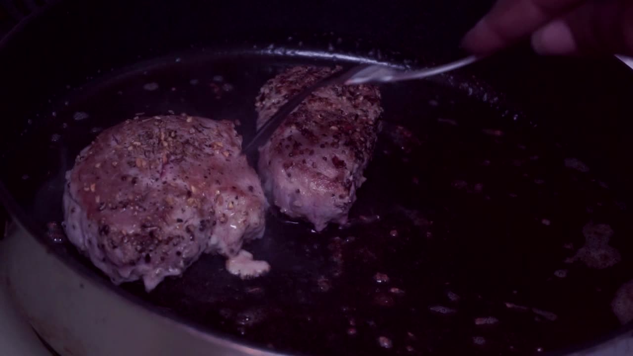 난로에서 요리하는 립아이 스테이크 흑인 여성 요리사가 요리할 때 고기를 뒤집습니다