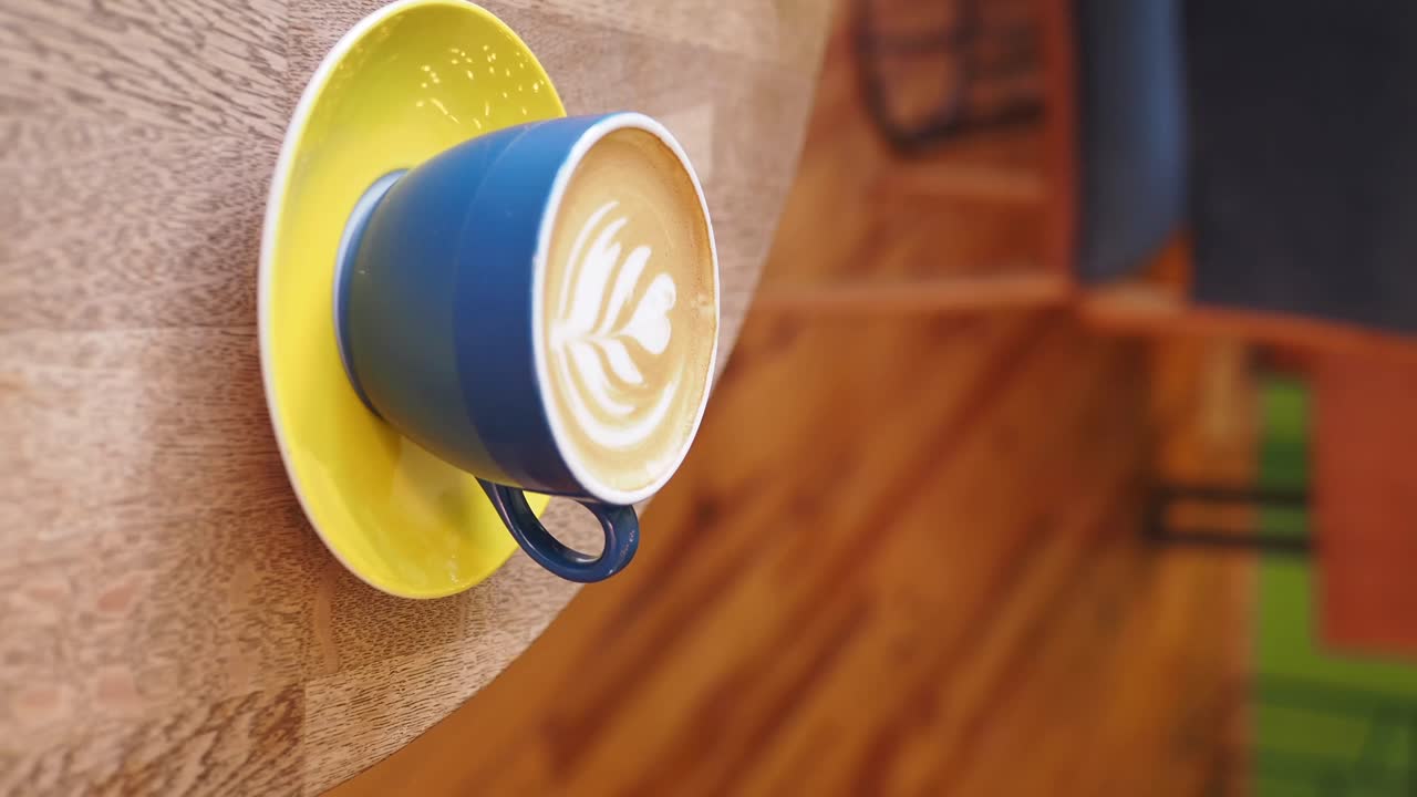 Latte art in a blue cup on a yellow saucer