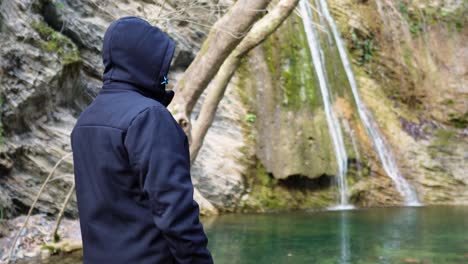 male hiker resting starring waterfall small lake creek zooming out