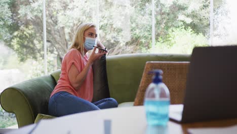 Woman-wearing-face-mask-talking-on-smartphone-at-home