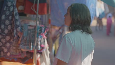 beautiful woman looking into colorful street market stalls in chiang mai, slow motion sho