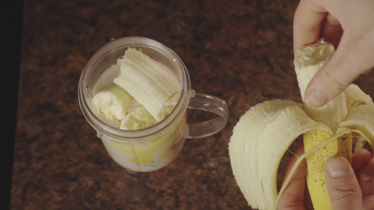 Persona che prepara uno smoothie alla banana con un frullatore personale