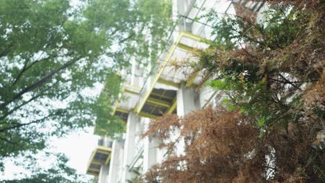 Steel-balconies-of-modern-urban-apartments-overlook-a-vibrant-mix-of-green-leaves-and-dry-pine-needles