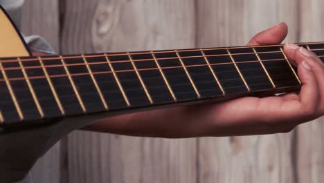 Hipster-playing-guitar-against-wooden-fence