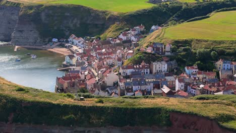 aerial drone view of staithes harbour on the north yorkshire coast with river,houses, boats on a sunny morning in august, summertime