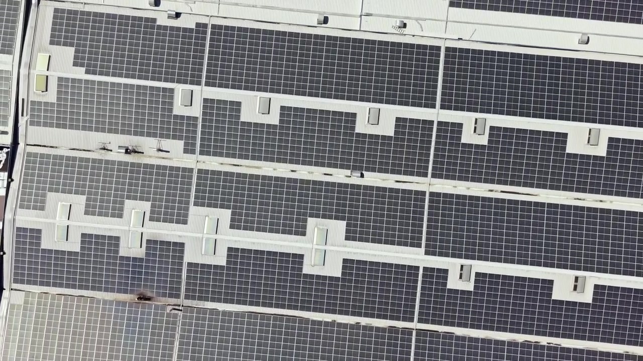 Pannelli solari coprono un grande tetto in una città, mostrando come l'energia pulita venga utilizzata per la produzione di energia durante le ore diurne.