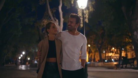 couple walking dark street enjoying date. smiling handsome man kissing woman