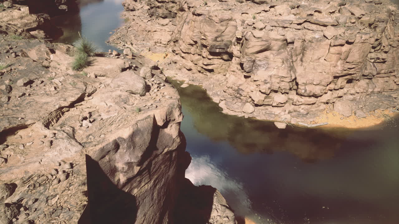 Rocky canyon landscape with river flowing through in bright sunlight