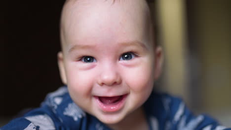 adorable caucasian kid laughing cheerfully to the camera. close up portrait of adorable baby boy with grey eyes.