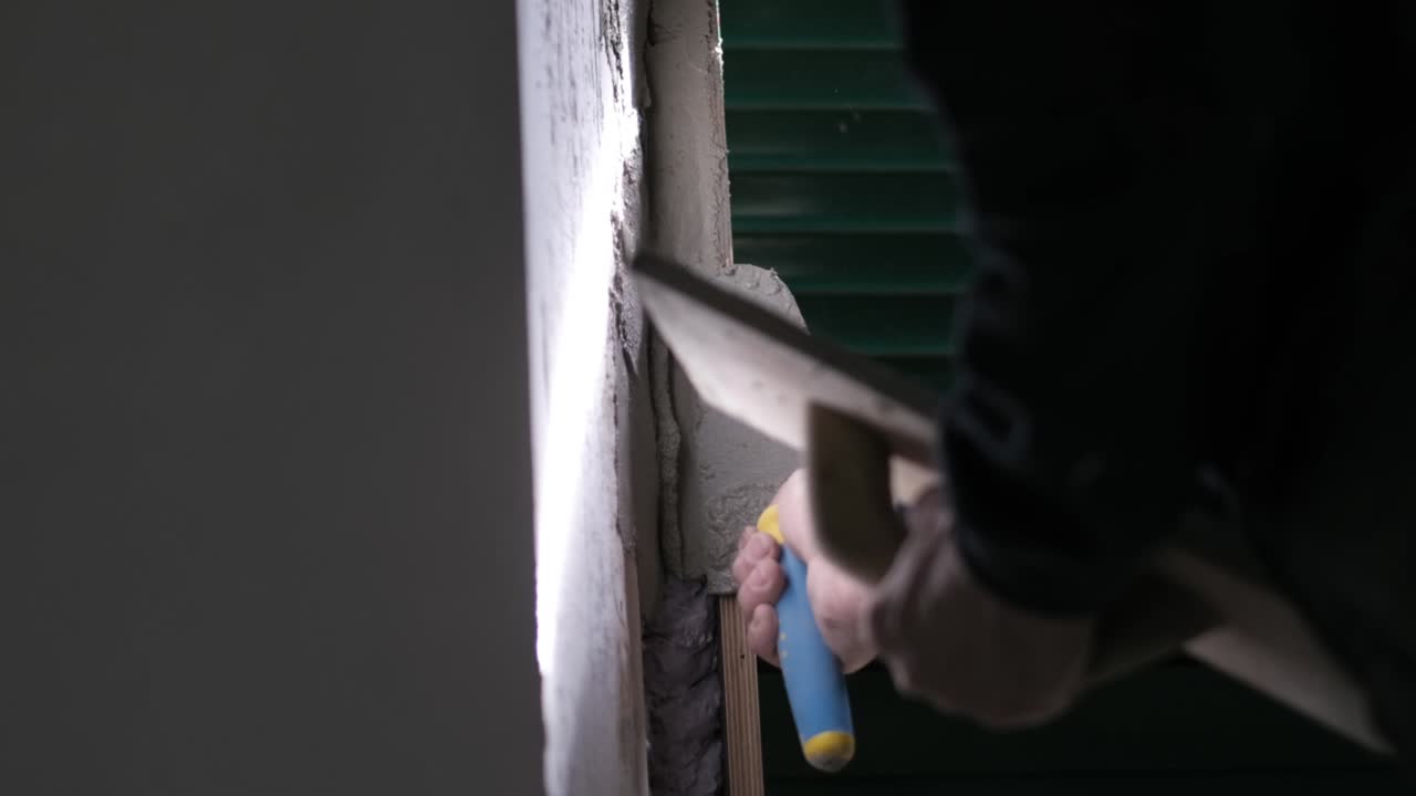 worker applying concrete of a wall near a window