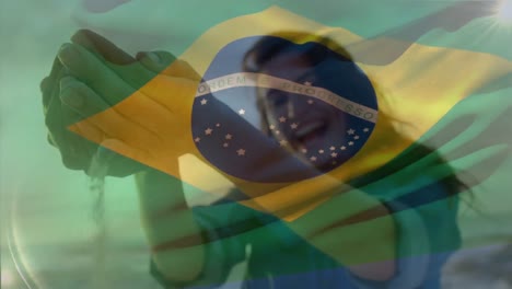 animation of flag of brazil over caucasian woman at beach