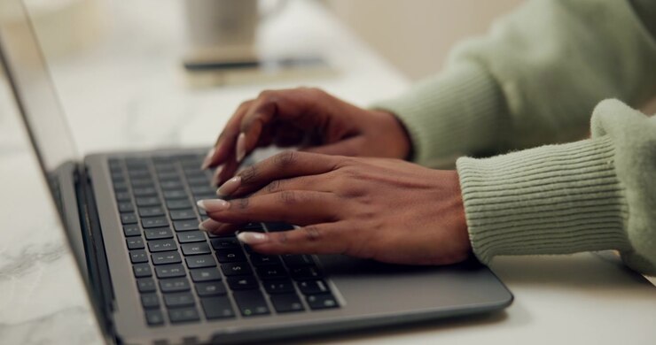 Primo piano di donna che digita sulla tastiera del laptop