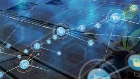 animación de una red de iconos digitales sobre un ingeniero masculino usando una computadora portátil cerca de paneles solares en el techo