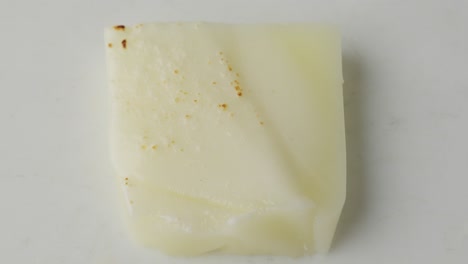 rebanada de queso mozzarella en escamas y quemada por la llama del soplador, cerrada de arriba hacia abajo