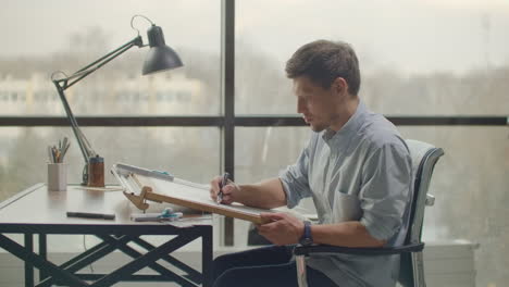 architect man sits at drafting table in modern industrial office during the day. architect working on blueprint with spesial tools and pencil close up. male architect at work only hands with ruler and pencil. design of the house. engineer. tools for drawing. creating a drawing.