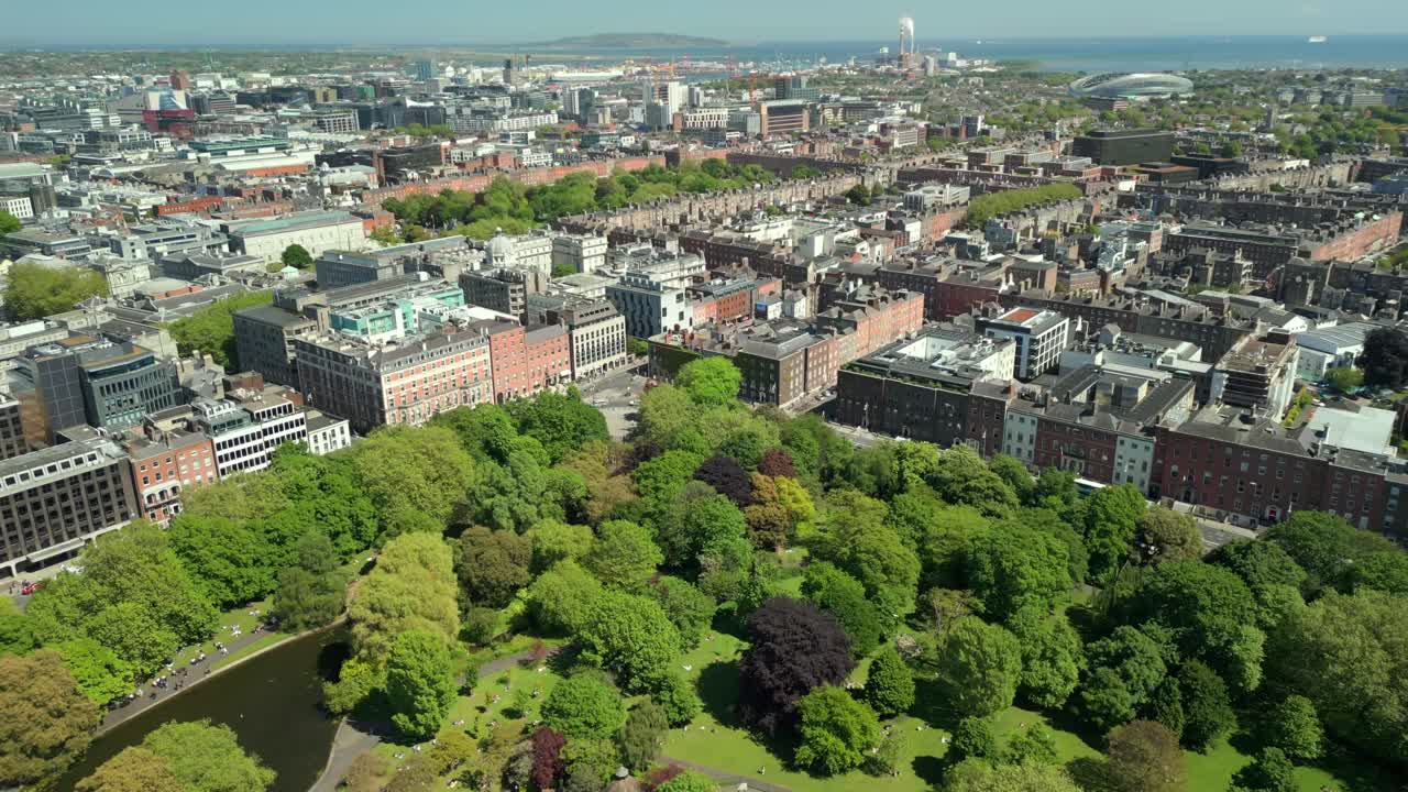 Ultra-wide reversing aerial video of St Stephen's Green and the surrounding area in Dublin City Centre, County Leinster, Ireland, on a bright and sunny day. Produced in 4K, 60FPS with Rec709 color.