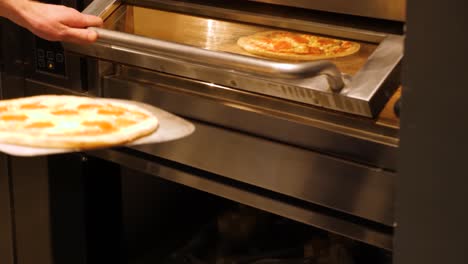 hot pizza being taken out of an oven