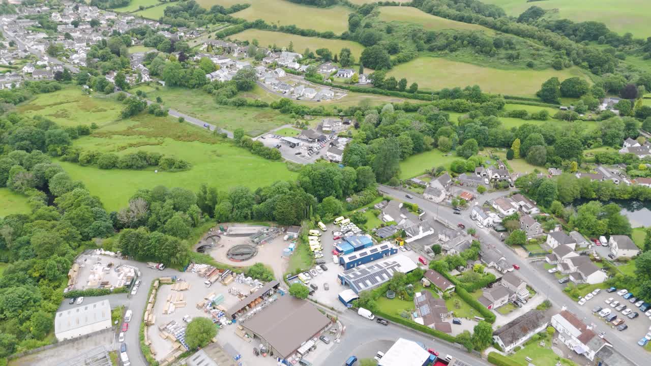 Aerial view of a village with houses, green fields, and an industrial area