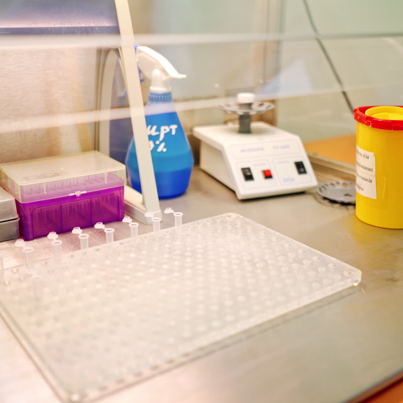 Hand of laboratory worker with tweezers on the table. Assistant putting empty sterile vials into the rack with tweezers in research clinic.