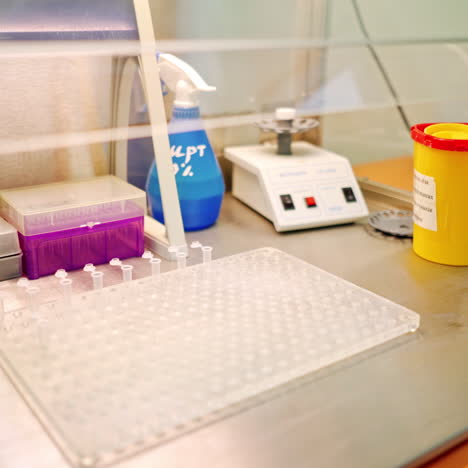 hand of laboratory worker with tweezers on the table. assistant putting empty sterile vials into the rack with tweezers in research clinic.