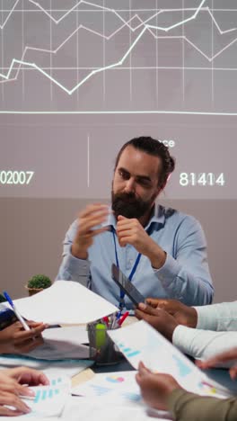 Vertical Video Business people prepare for a pitch by studying financial data on files reports