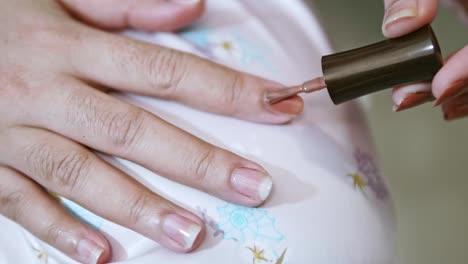 el primer plano de una mujer pinta sus uñas con una manicura hecha a sí misma en la escena de cámara lenta en casa