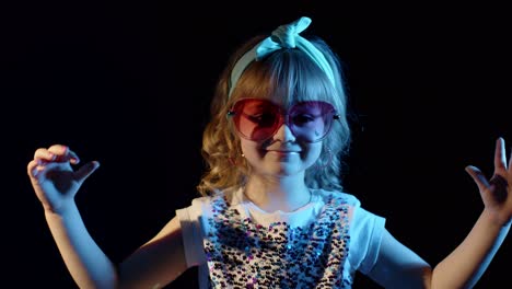 Stylish-girl-looking-at-camera,-smiling,-showing-heart-sign-in-neon-lighting-posing-at-disco-club