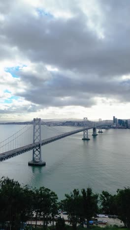 push-in drone shot of the bay bridge from yerba buena island, revealing san francisco's skyline and cityscape across the bay