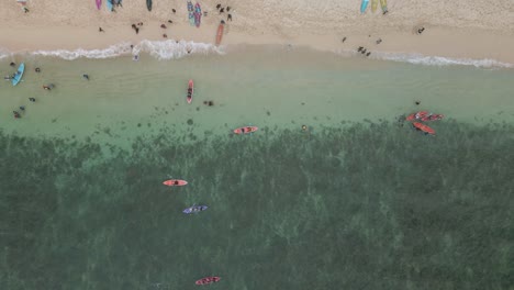 Beach fun with kayaks and sunbathing in Indonesia, aerial top down view