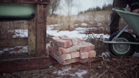 The-Man-is-Removing-Bricks-From-the-Wheelbarrow-for-Use-in-the-DIY-Hot-Tub---Static-Shot