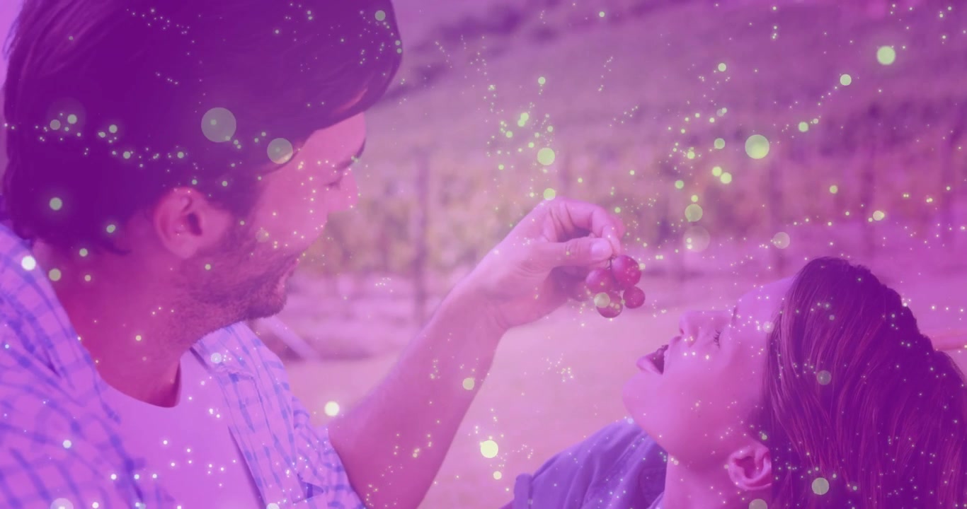 Uomo che dà da mangiare uva a una donna in un vigneto con effetti di luce magici