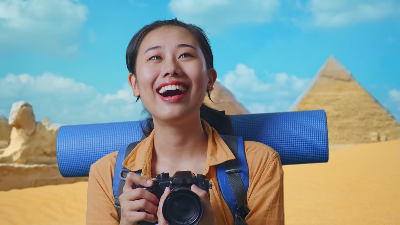 Close Up Of Asian Female Hiker With Mountaineering Backpack Smiling And Holding A Camera In Her Hands Then Looking Around While Traveling In Pyramid Of Giza